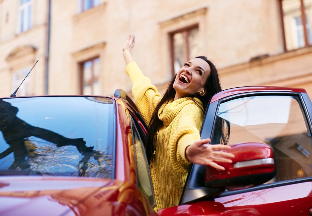 The girl rejoices in life and sits in her red car